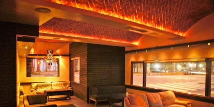 Layered paper cut-out collage of a warm amber lounge interior with soft glowing rectangles and shadowy furniture shapes